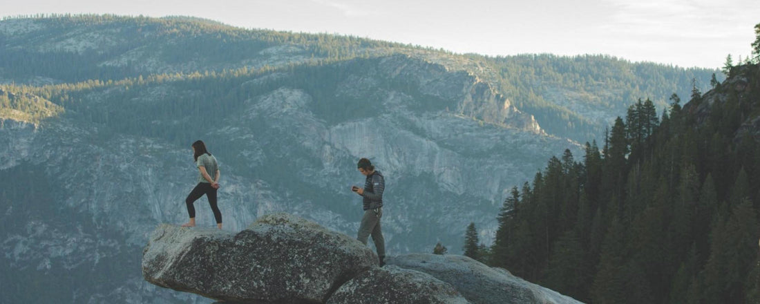 Two hikers in the mountains standing on a cliff edge